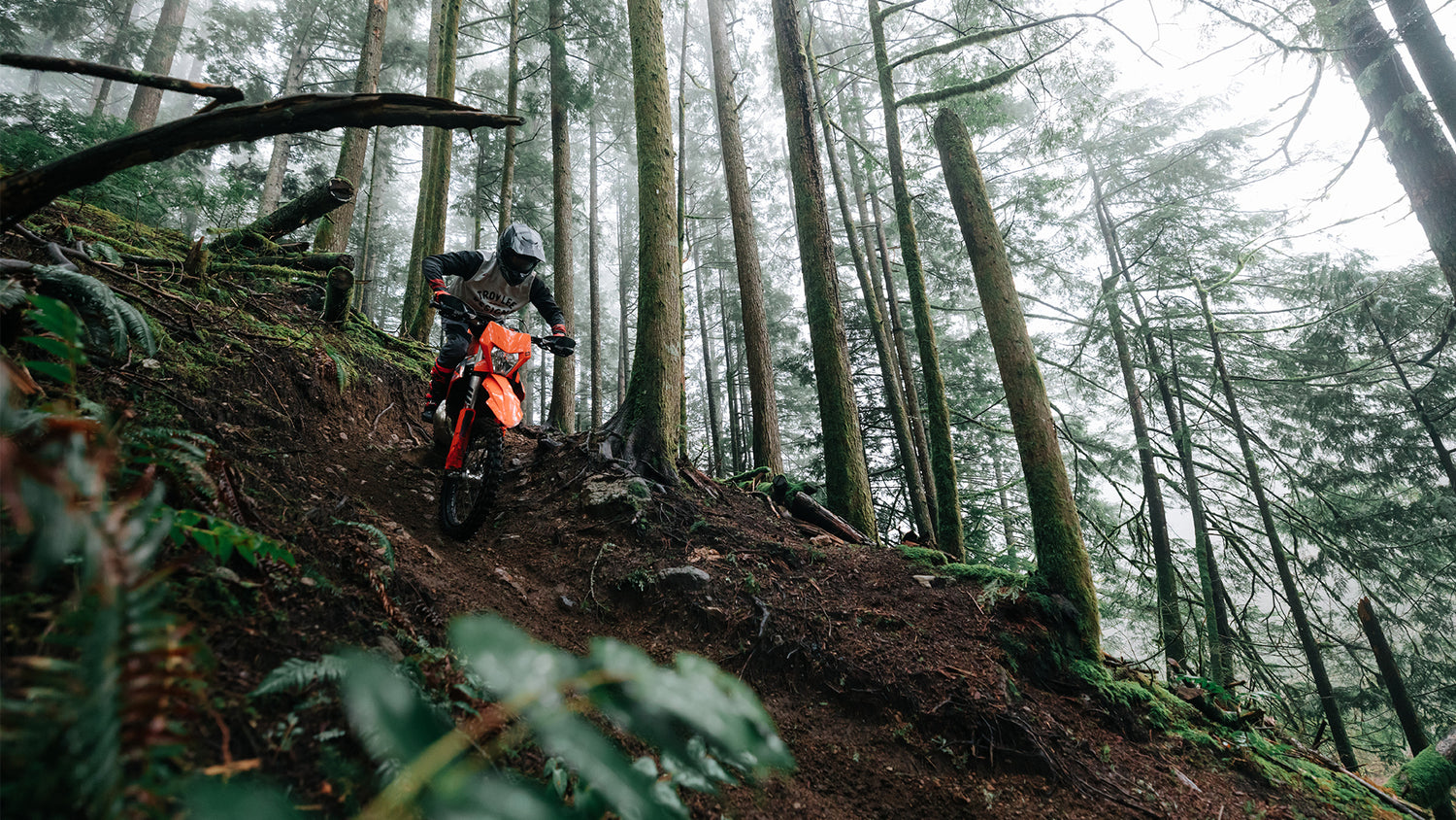 Scout GP motorcross rider in a forest, going down a hill